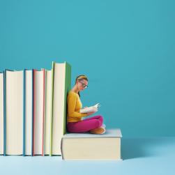 Photo d'une jeune femme assise sur un livre géant