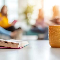 Tasse de café avec un livre et des personnes en arrière plan
