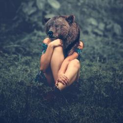 Une femme avec une tête d'ours assise dans l'herbe