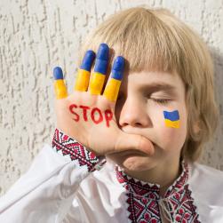 Un enfant se cache derrière sa main avec écrit &quot;STOP&quot;