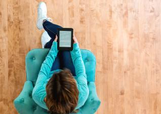 Une femme sur un fauteuil lit une liseuse